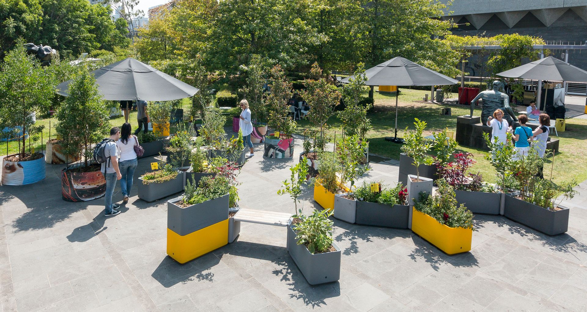 A series of metal planters and seating arranged loosely on a forecourt